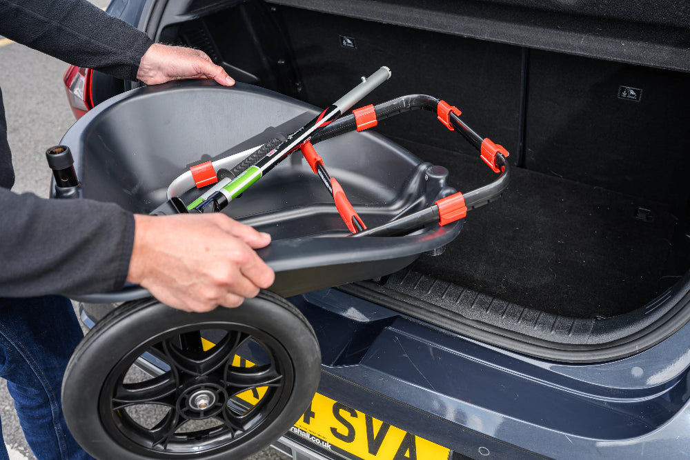 Person loading a folded handi cartinto a car trunk