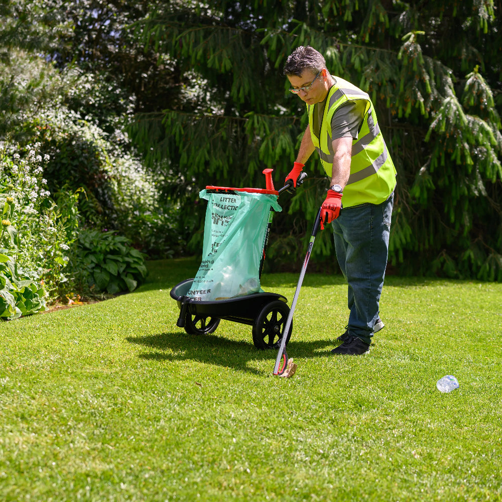Person using a garden tool on a grassy area with trees in the background