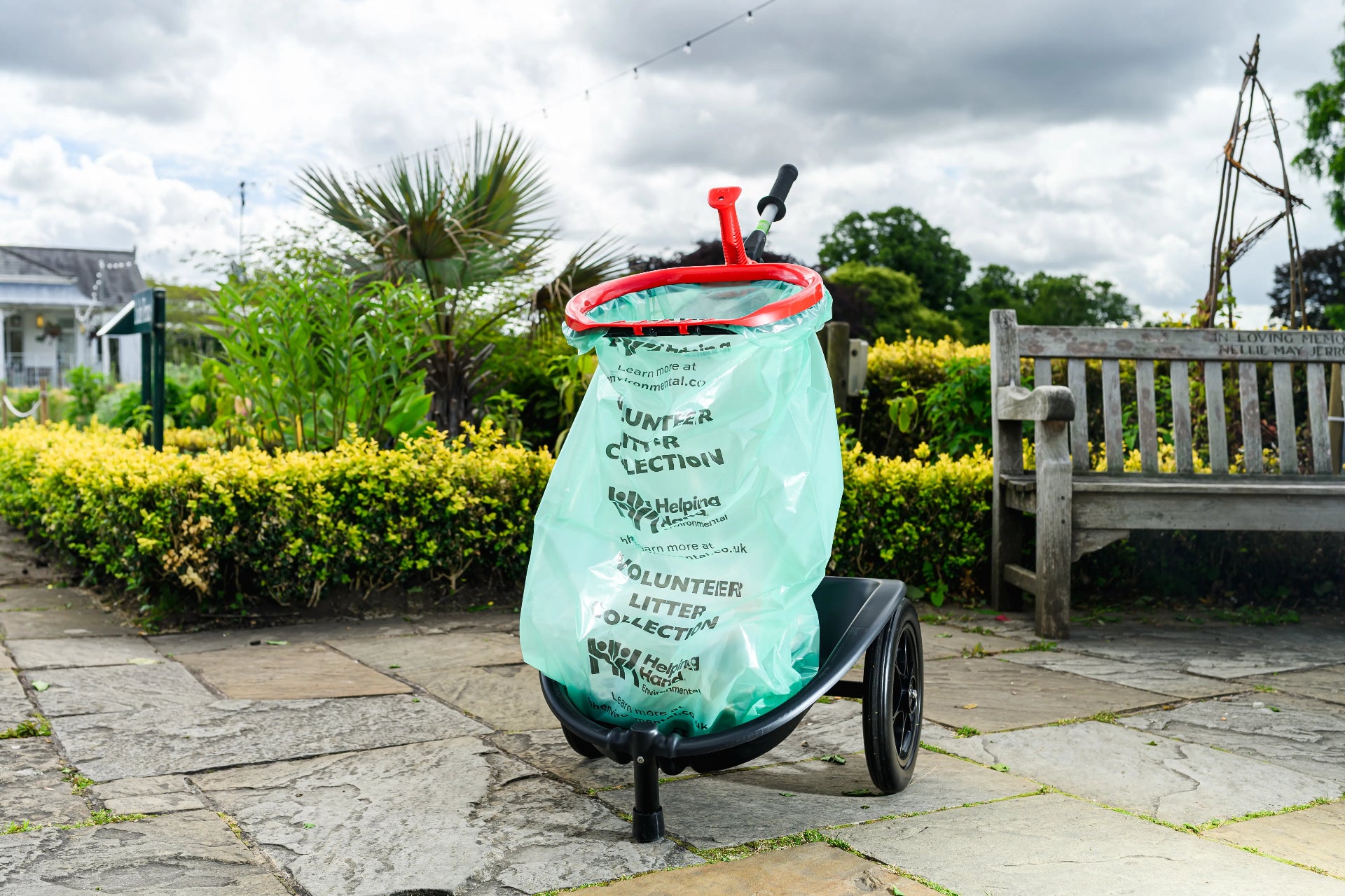 A litter cart in a park with a full bag of litter