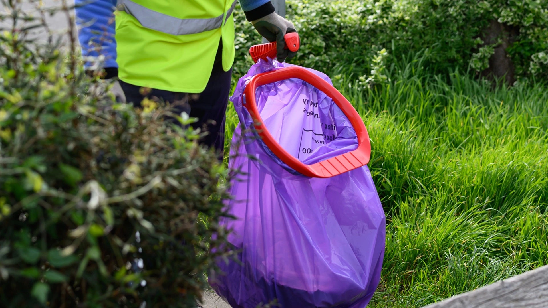 Someone using a litter picking hoop with a full bin bag