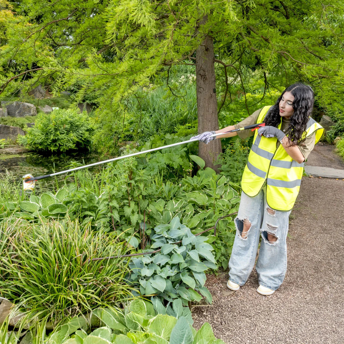 Volunteer worker picking trash from a pond with Streetmaster Pro, extra long litter picker.
