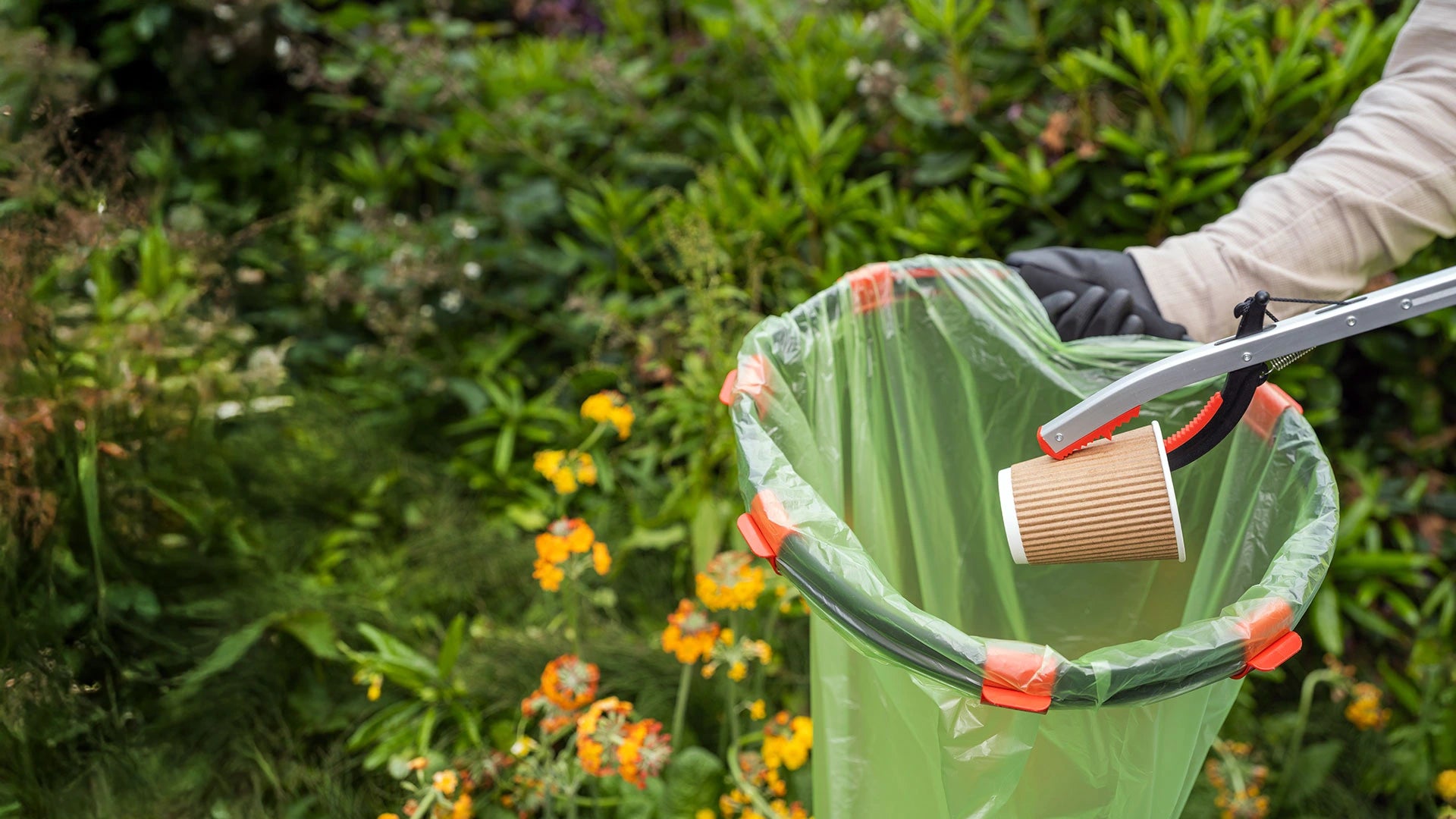 Volunteer using a Handi Hoop with clips to collect waste outdoors.