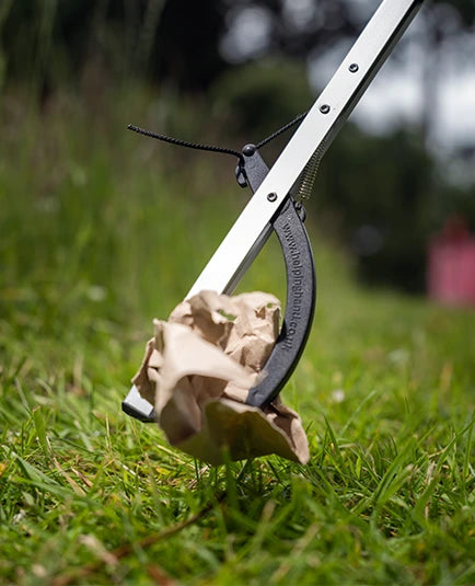 Litter picker grabbing paper trash on field.