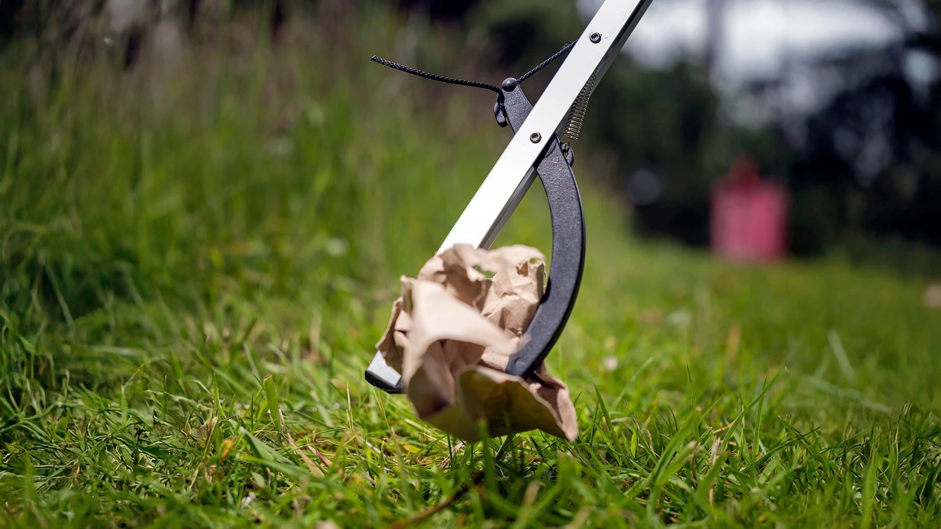 Close up of litter picker gripping paper trash outside.