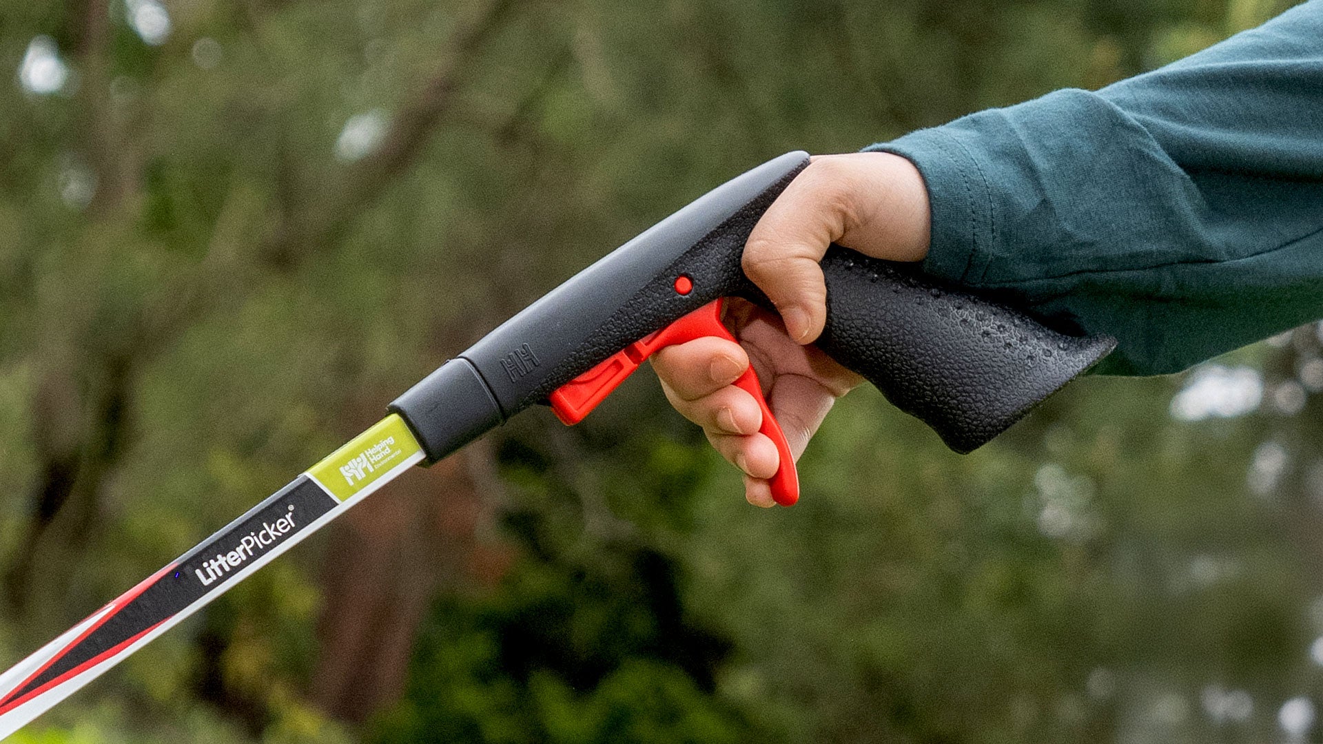 Person gripping a Litter Picker Handle with a blurred green background.