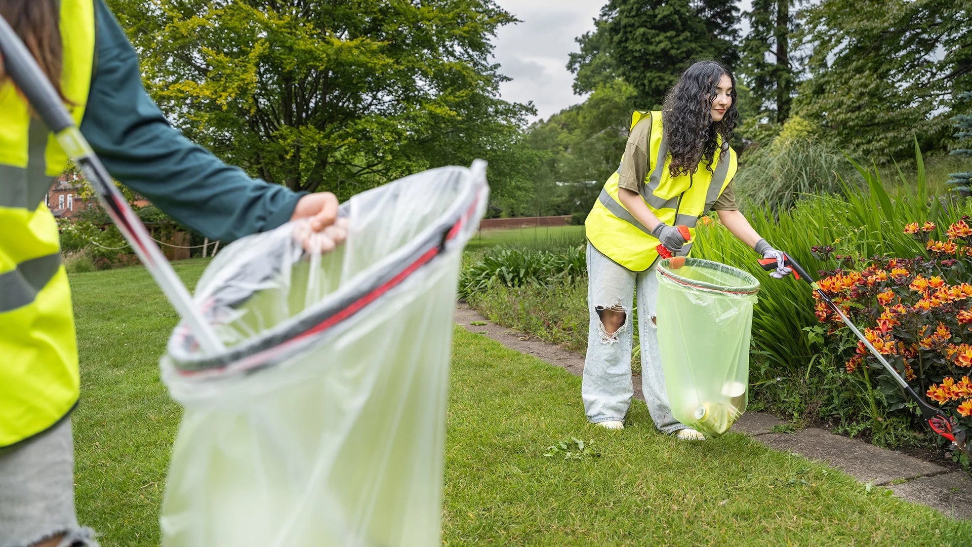 Person in high-visibility vest cleaning up a garden with a litter picker and a Handi Hoop.