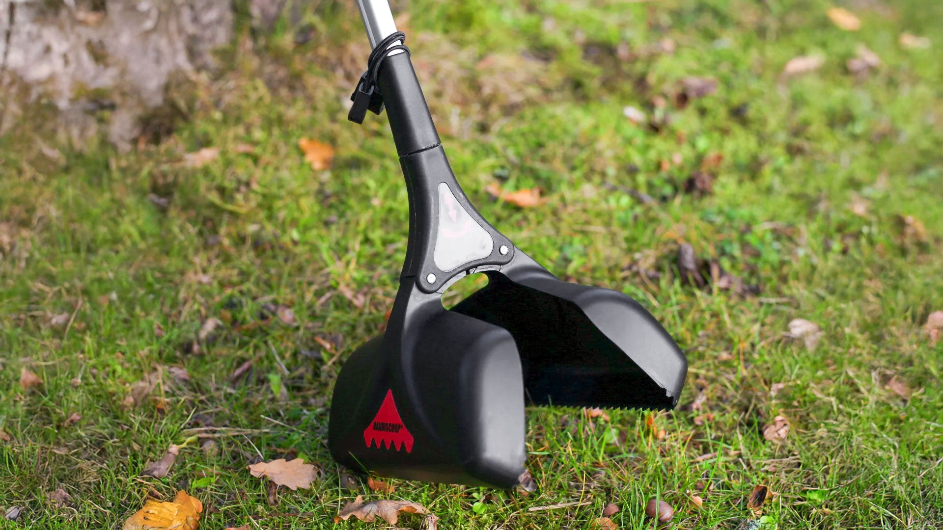 Handi Scoop pooper scooper picking animal waste on grass terrain.
