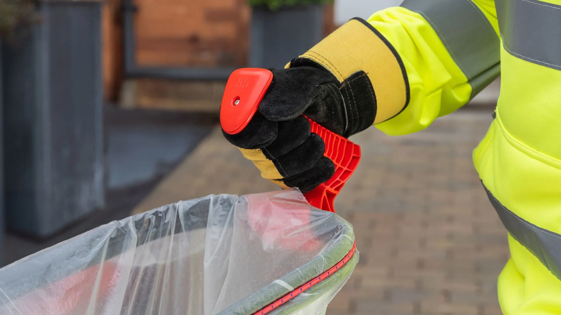 Person wearing a high-visibility jacket grabbing Handi Scoop Plus handle.