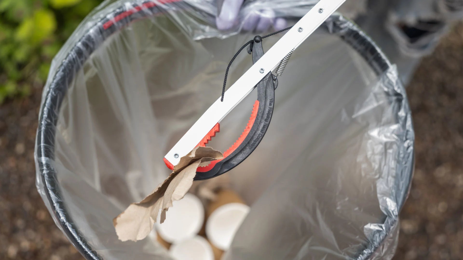 Litter picker grabbing paper trash outside.