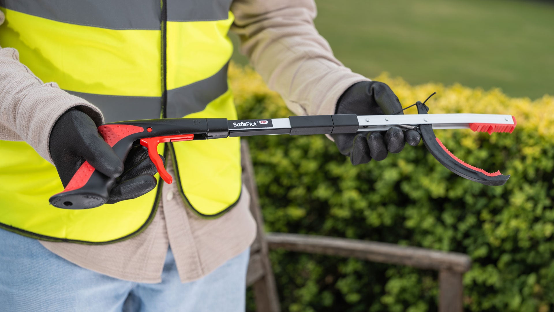 Person wearing a high-visibility vest holding SafePick Folding litter picker.