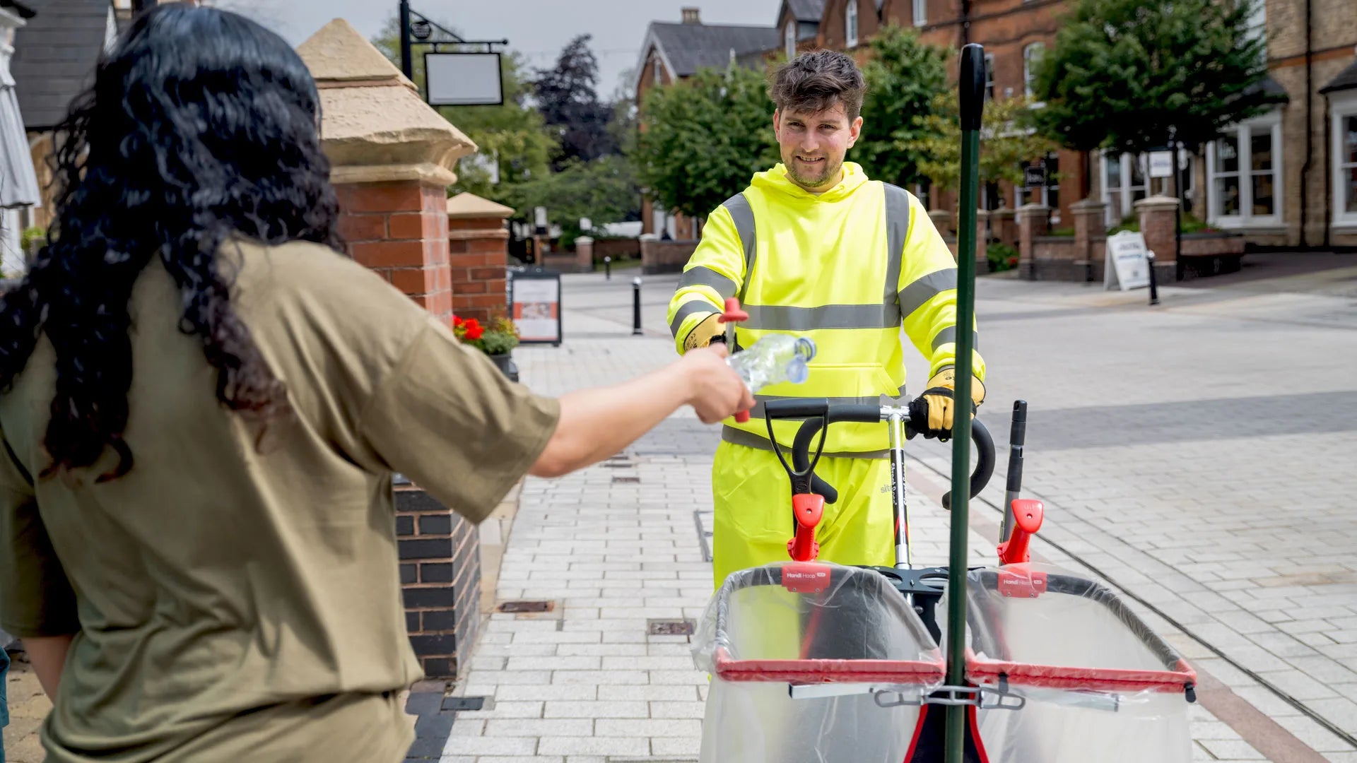 Person in a high-visibility jacket pushing commercial street cart.