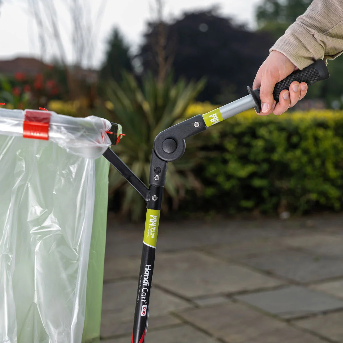 Person using Handi Cart Litter Trolley with a clear bag attached outdoors.