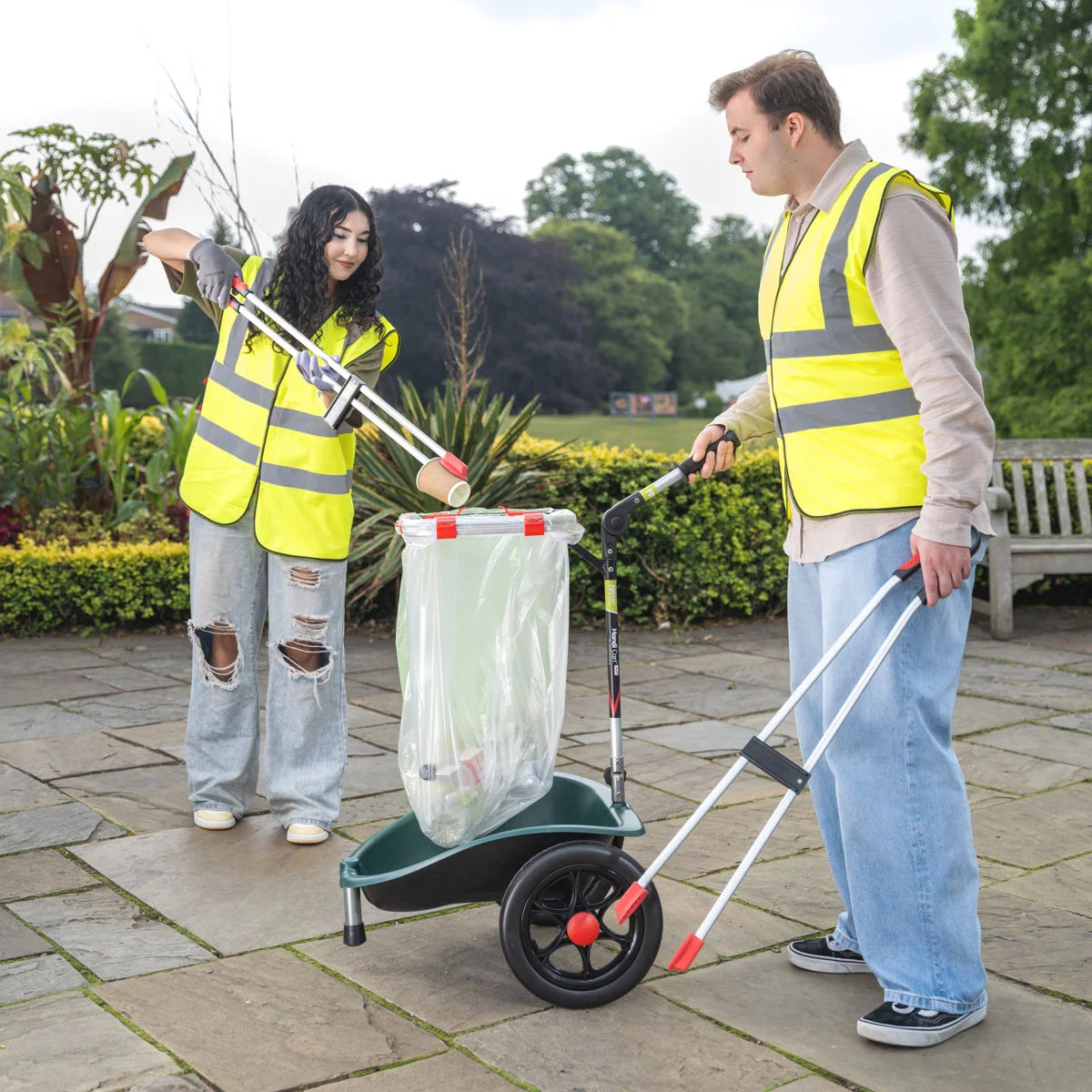 Volunteers in a garden disposing trash in the Handi Cart Duo litter trolley.
