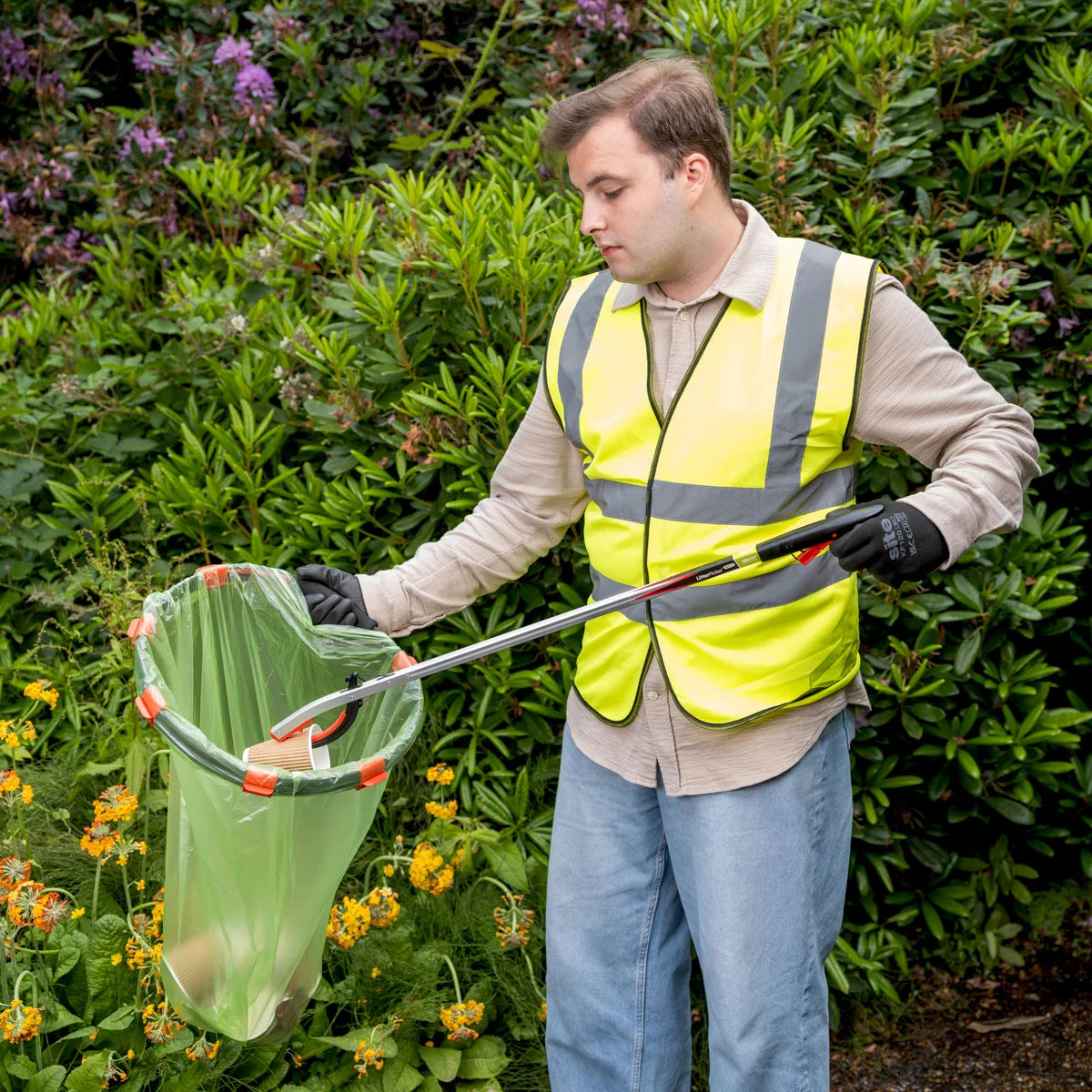 Person in a garden using a litter picker to grab trash and dispose in Handi Hoop Clip.