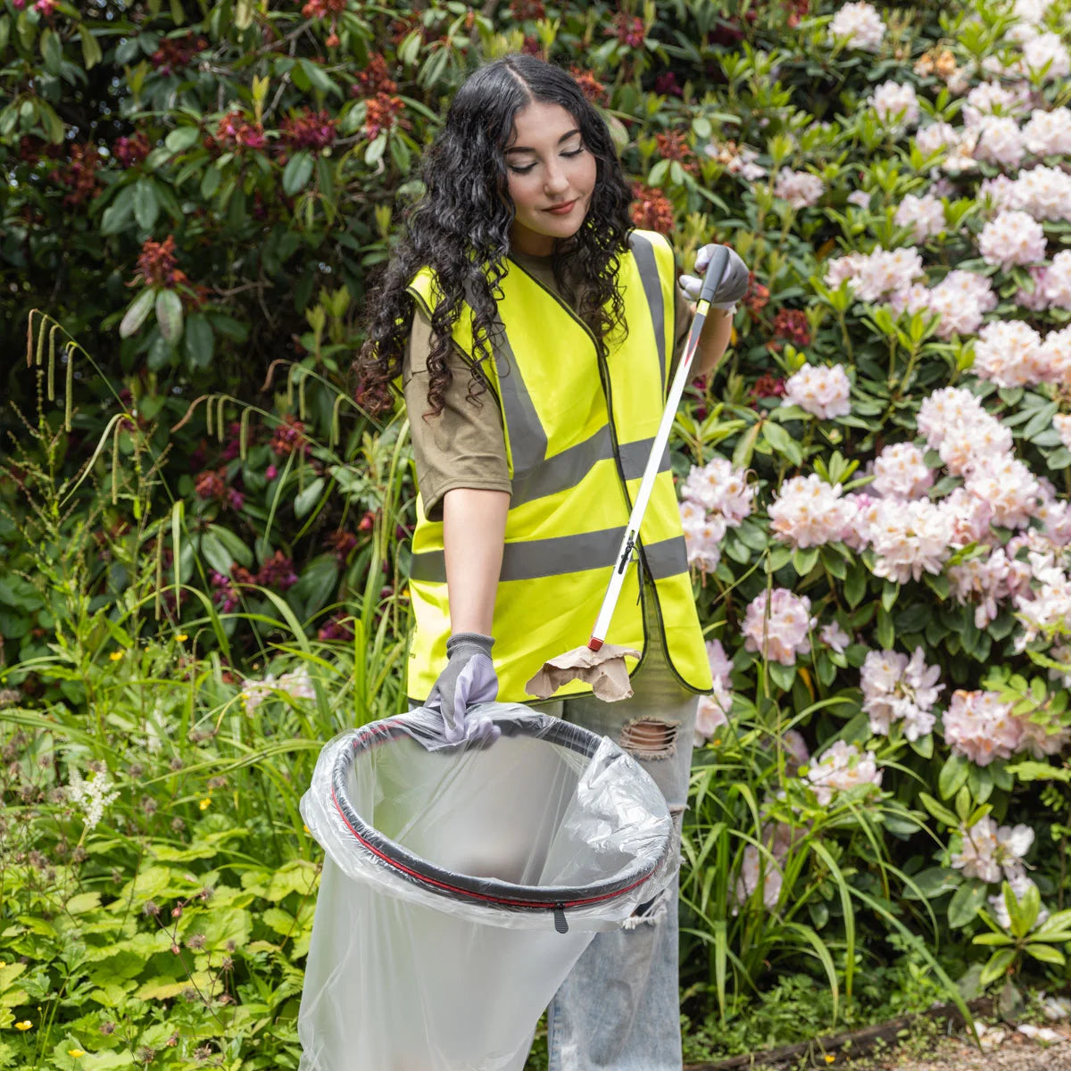 Person in high-visibility vest using a litter picker to collect trash in the Handi Hoop Foam bungee cord litter hoop.