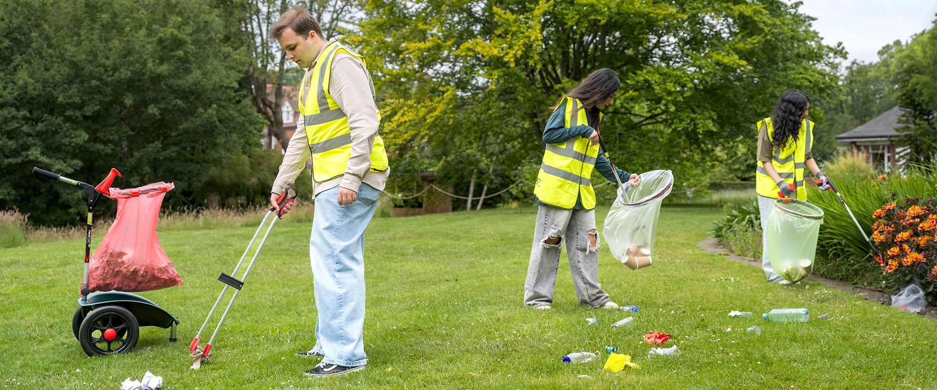 Volunteers in a park litter picking with litter bins.