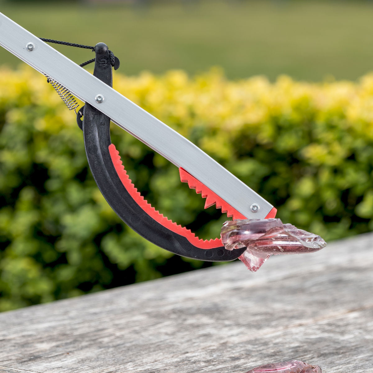 Person with a litter picker grabbing broken glass.