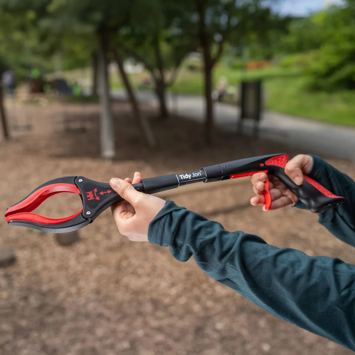 Person holding a Tidy Jon Litter Picking Stick with a blurred park background.