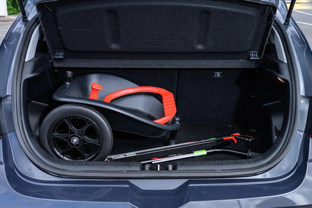 Open car trunk with a folded litter cart inside
