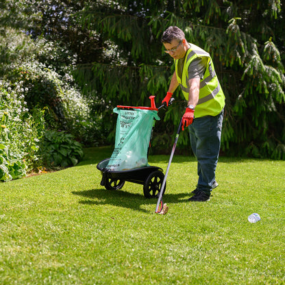Person using a garden tool on a grassy area with trees in the background