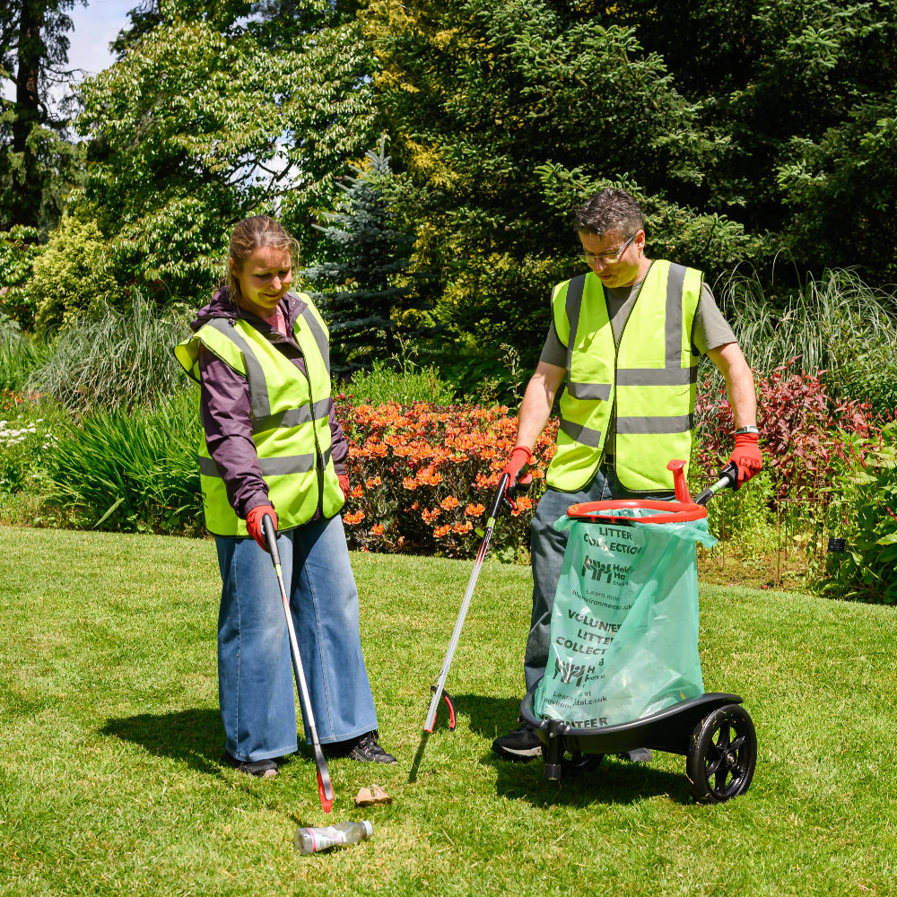 Two people in high-visibility vests using litter picking tools in a park setting.