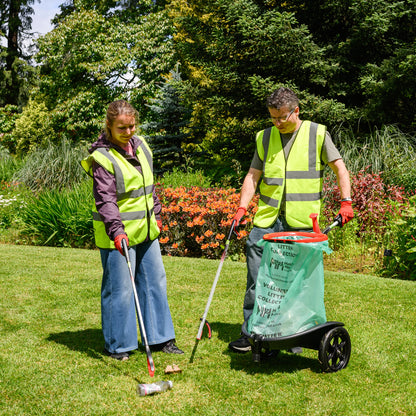 Two people in high-visibility vests using litter picking tools in a park setting.
