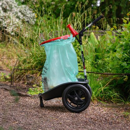 Garden waste collection cart with a green bag on a garden path