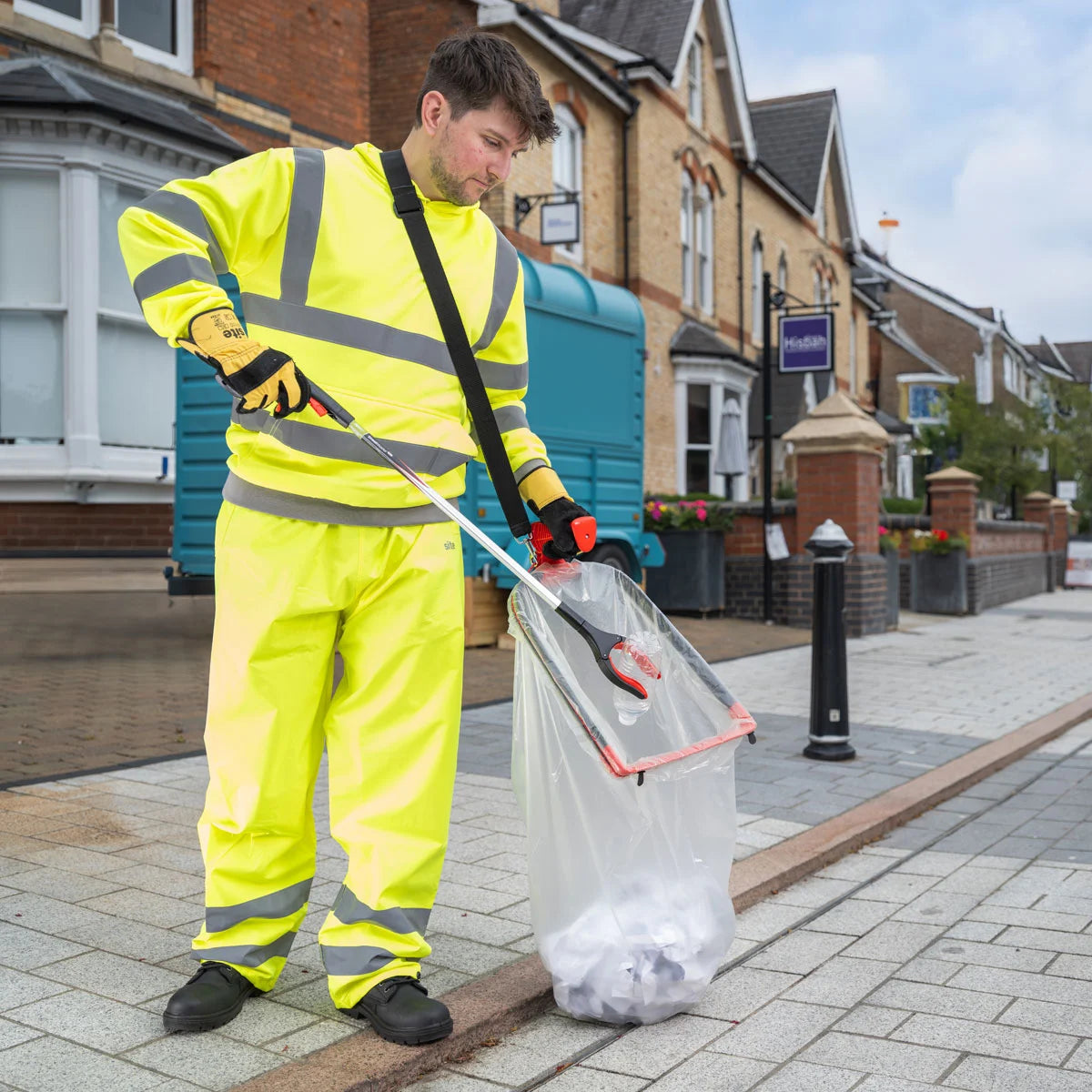 Person in high-visibility clothing cleaning a street with Streetmaster pro litter picker.
