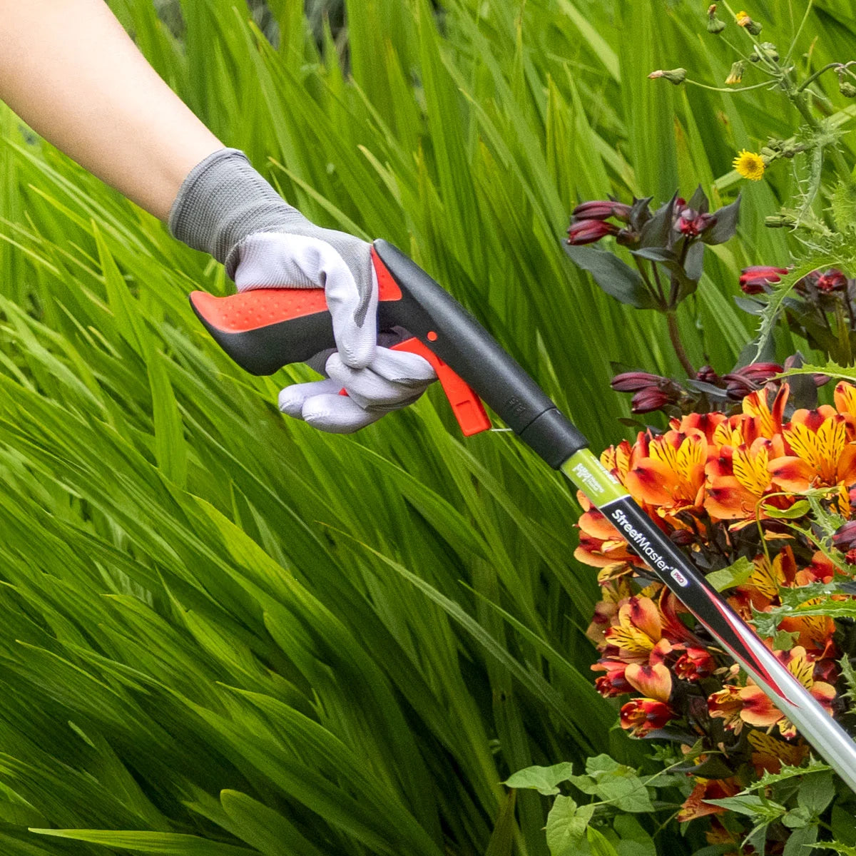 Person using a Streetmaster Pro litter picker surrounded by colorful flowers.