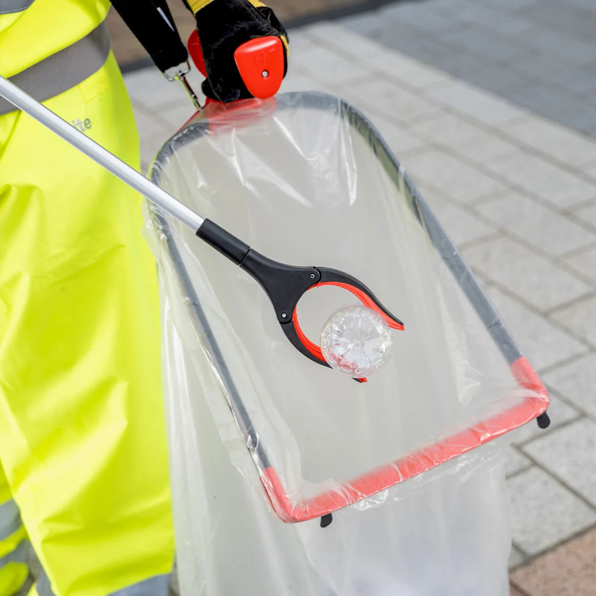 Person using Streetmaster Pro rotating head litter picker to pick up plastic bottle.