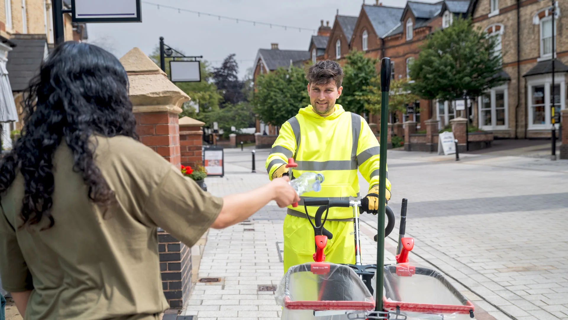 A person passing a plastic bottle to a volunteer to recycle litter with litter picking tool-station. 
