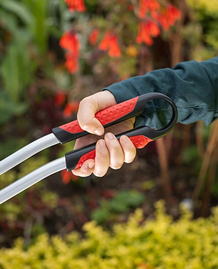 Person holding a heavy duty litter picker against a blurred garden background.