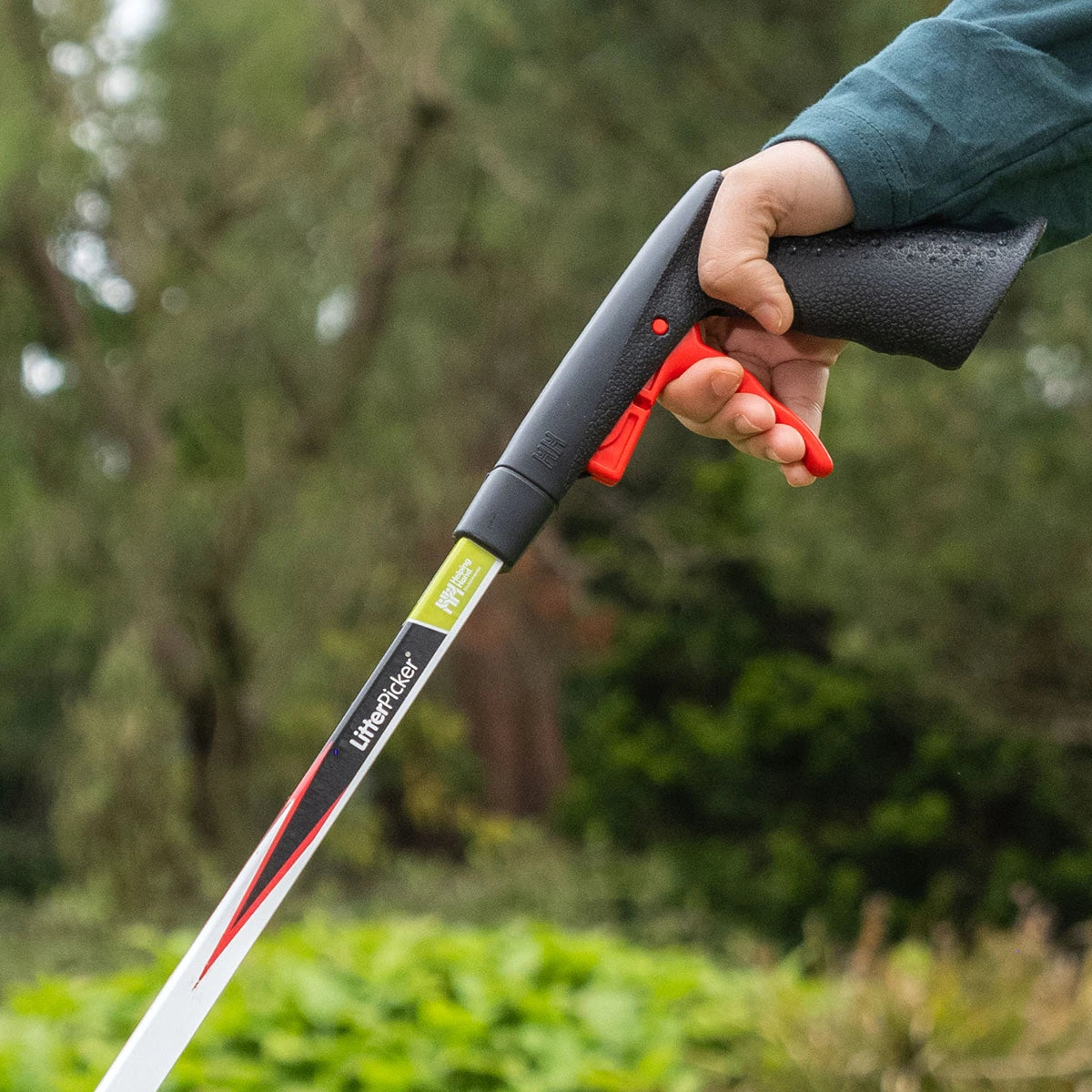 Person holding litter picking stick with a blurred natural background.