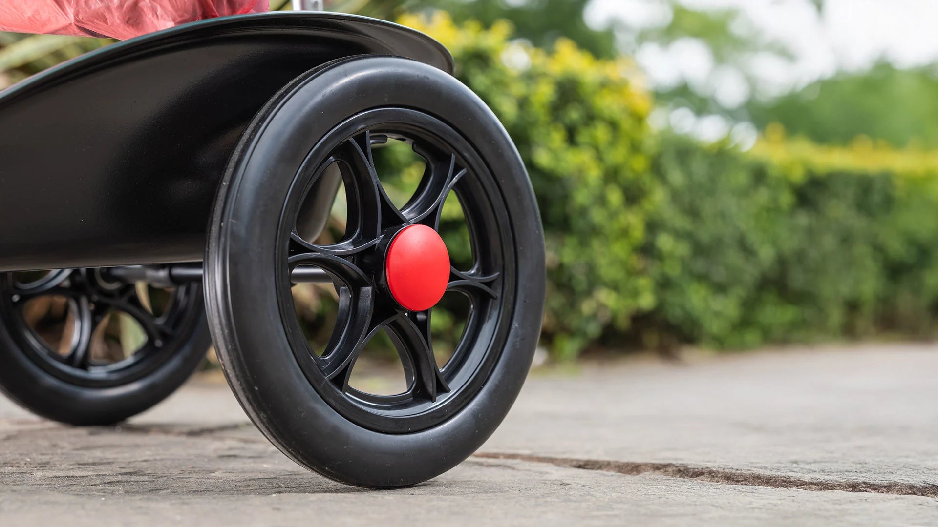 Close-up of Handi Cart Lite wheel with blurred greenery in the background.