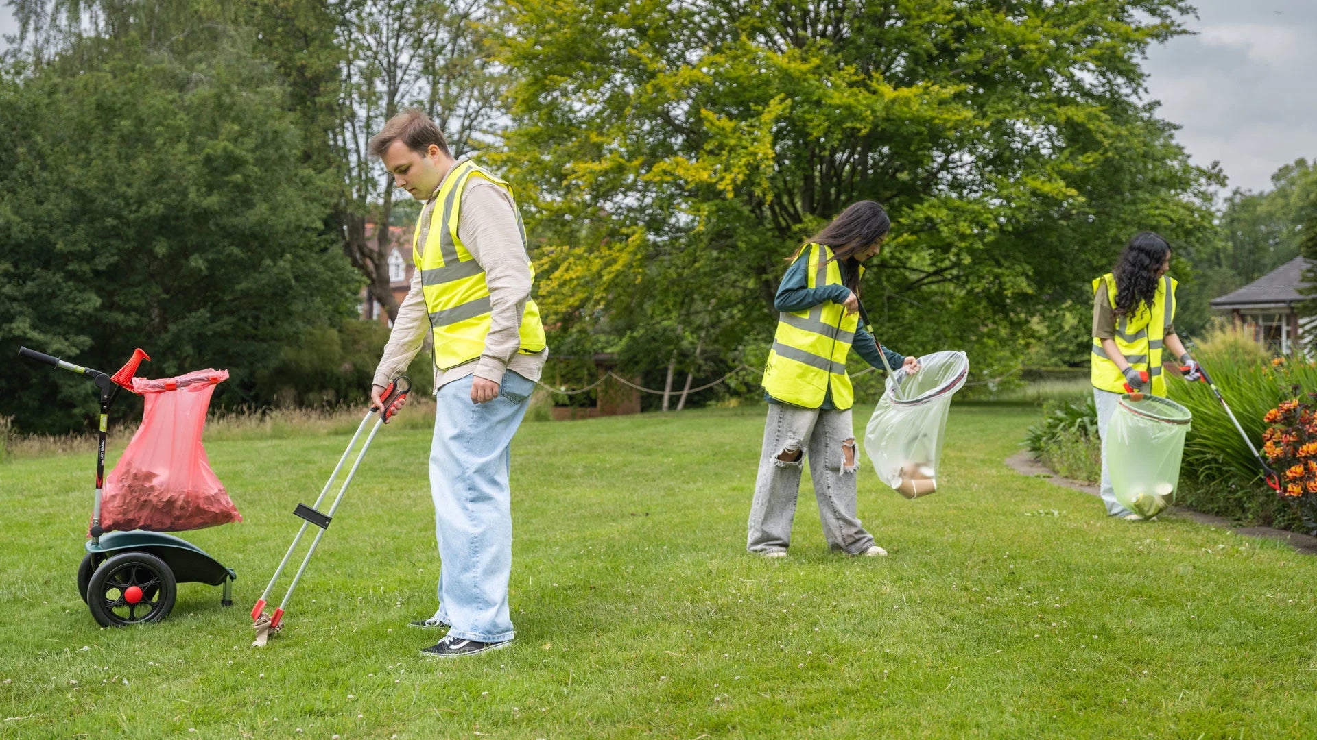 Three people in high-visibility vests cleaning up a park with litter pickers and Hand Cart Lite.