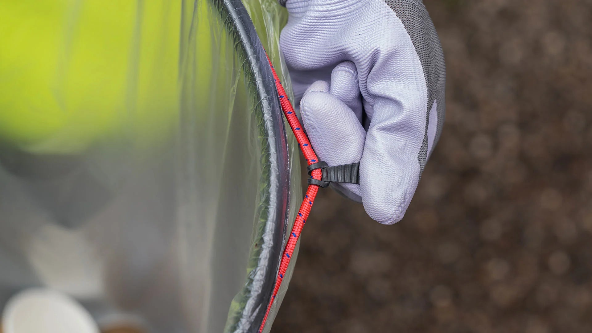 Close-up of a gloved hand holding a handi hoop bungee cord. 