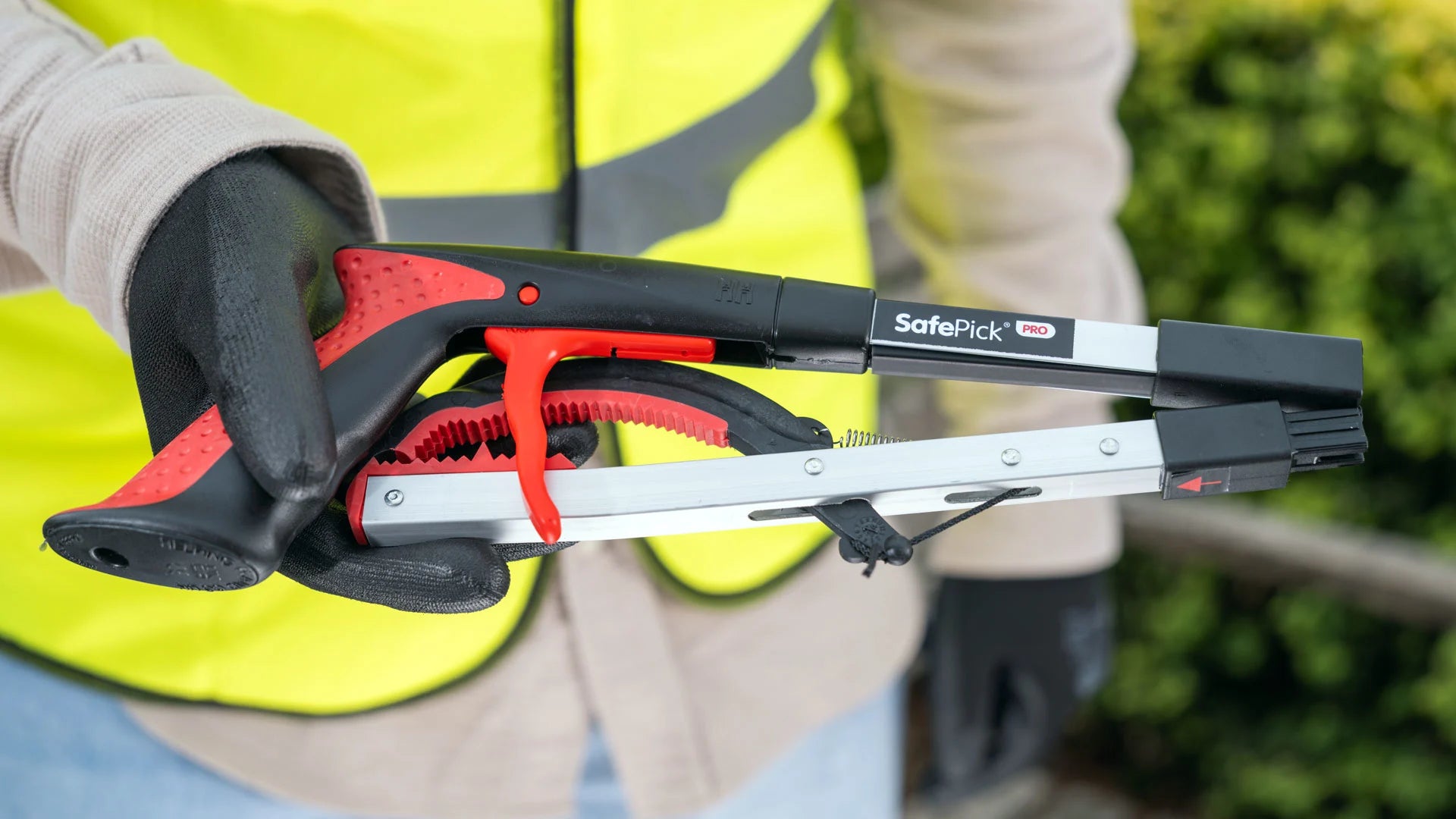 Person holding the SafePick PRO folded litter picker in a garden.