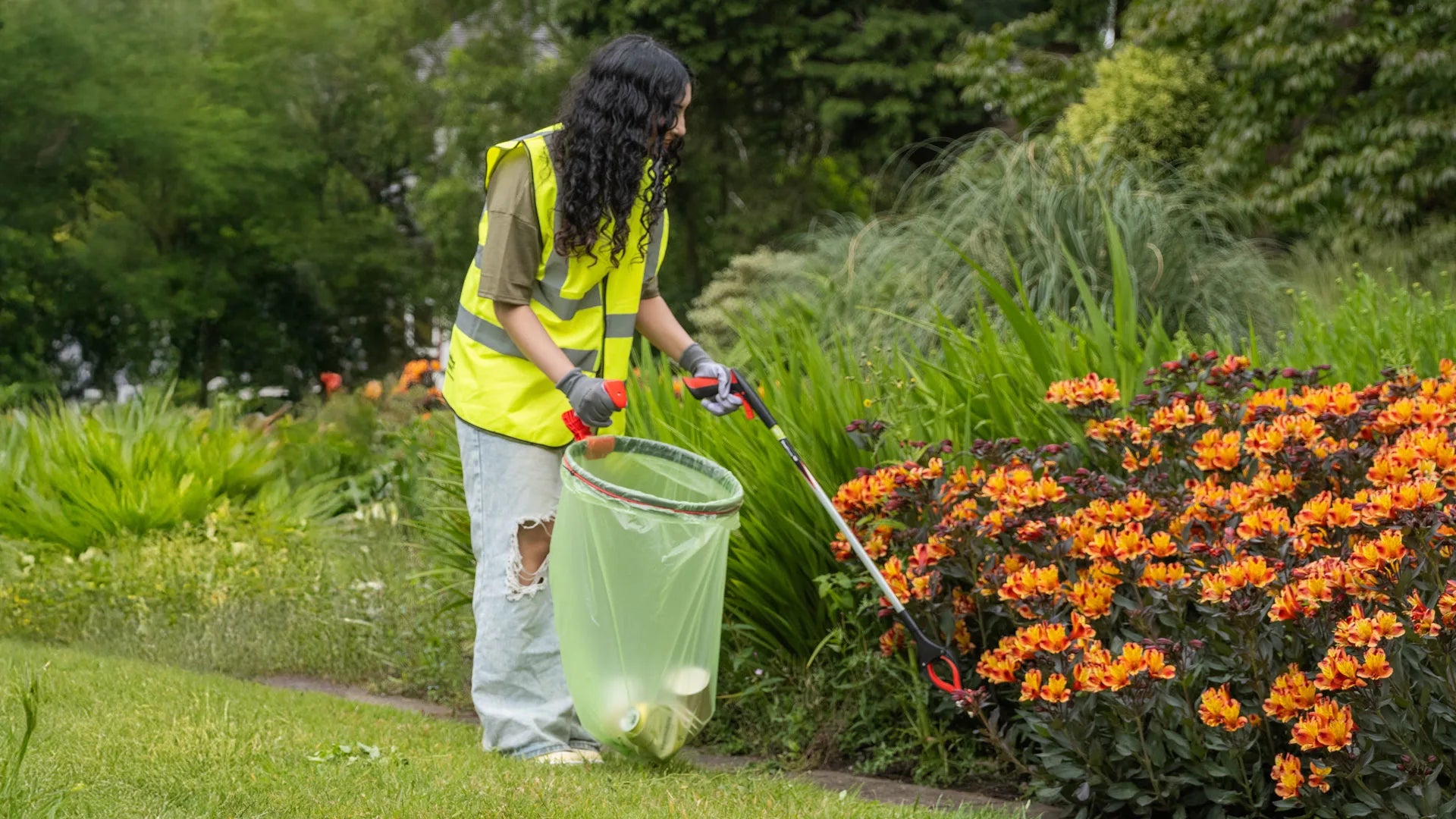 Person picking up litter in a garden using the Streetmaster Pro Gel litter picker.
