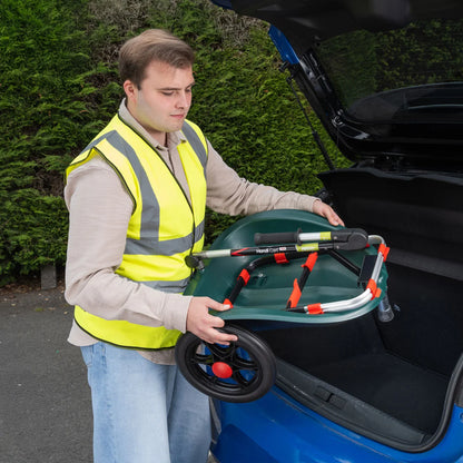 Man in a high-visibility vest putting Handi Cart Duo litter trolley open car trunk.
