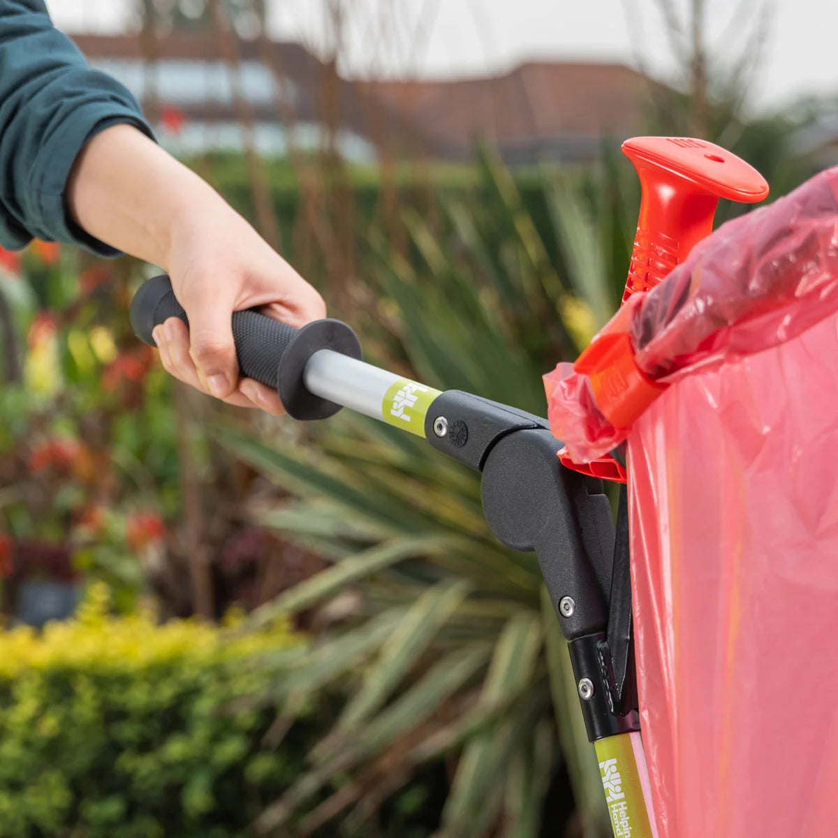 Person grabbing Handi Cart Lite litter picking trolley outdoors. 