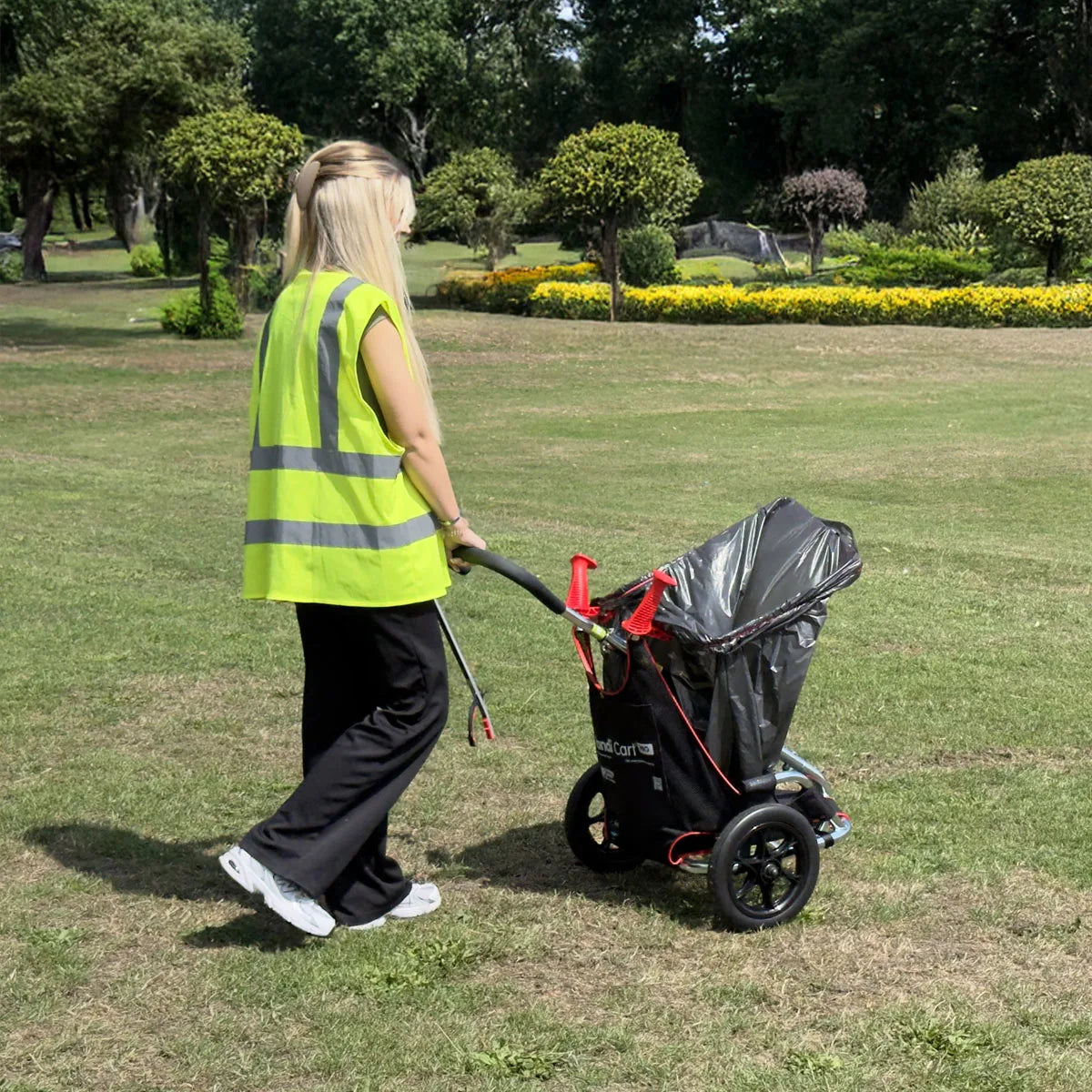 Volunteer in a yellow safety vest pushing Handi Cart Pro Litter Picking Cart.
