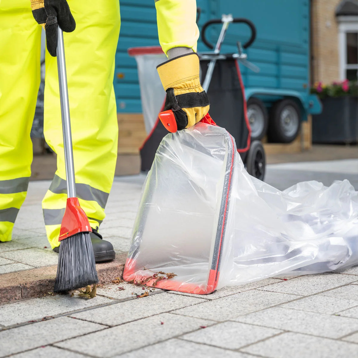 Person cleaning a sidewalk with a broom and Handi Hoop Plus Litter Hoop.