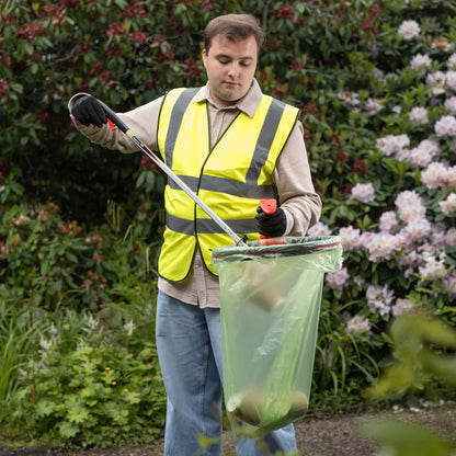 Man in a high-visibility vest using a litter picker to put trash in the Handi Hoop Pro litter hoop.