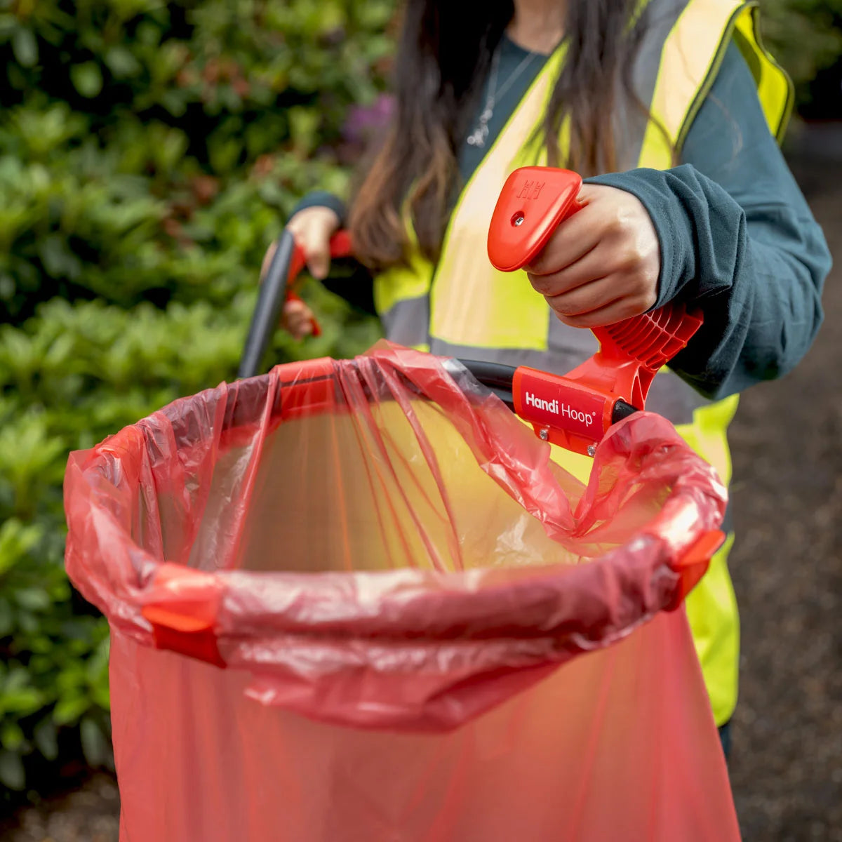 Volunteer grabbing Handi Hoop Pro Clip litter hoop at a park.
