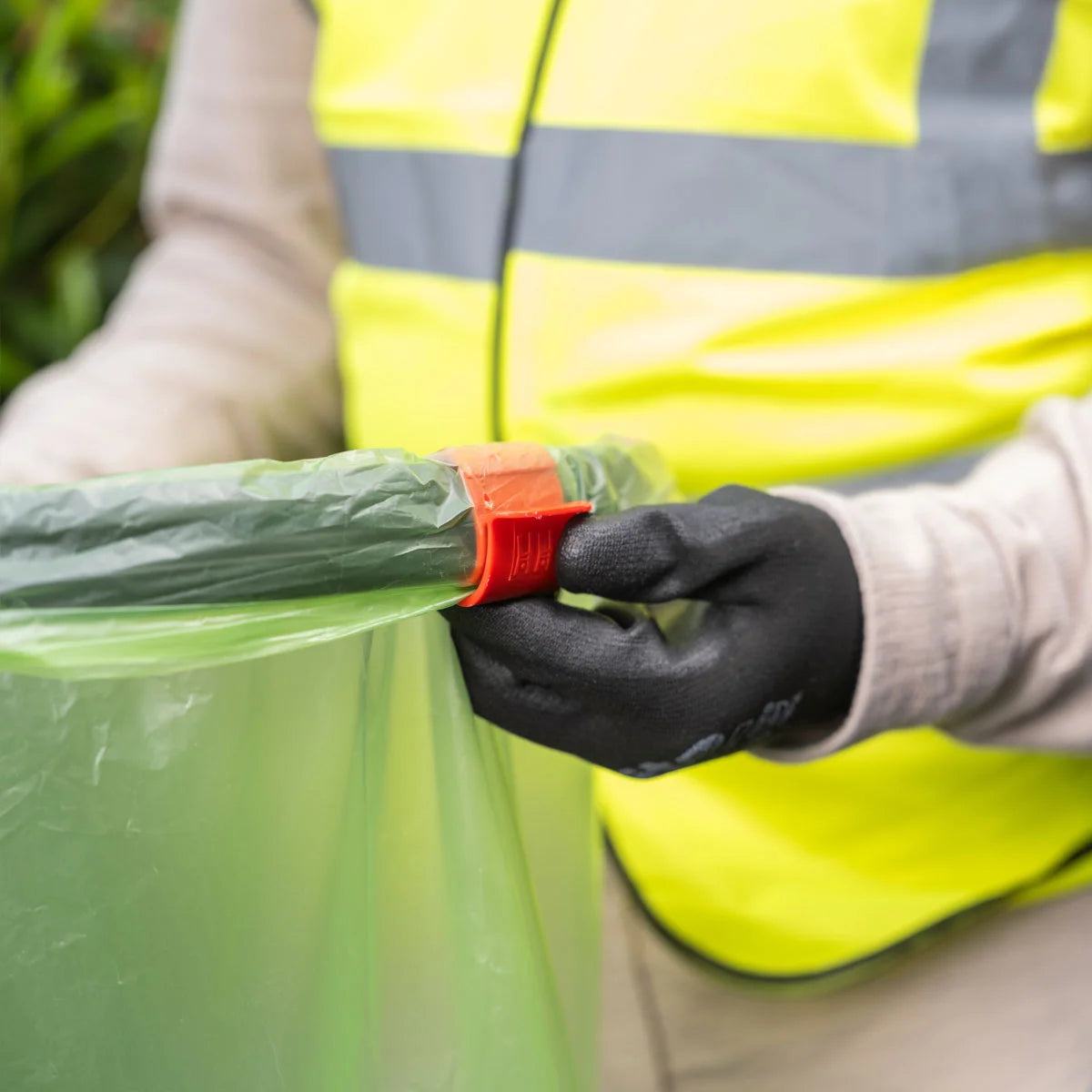 Person wearing a high-visibility vest holding a Handi Hoop Pro Clip litter hoop.