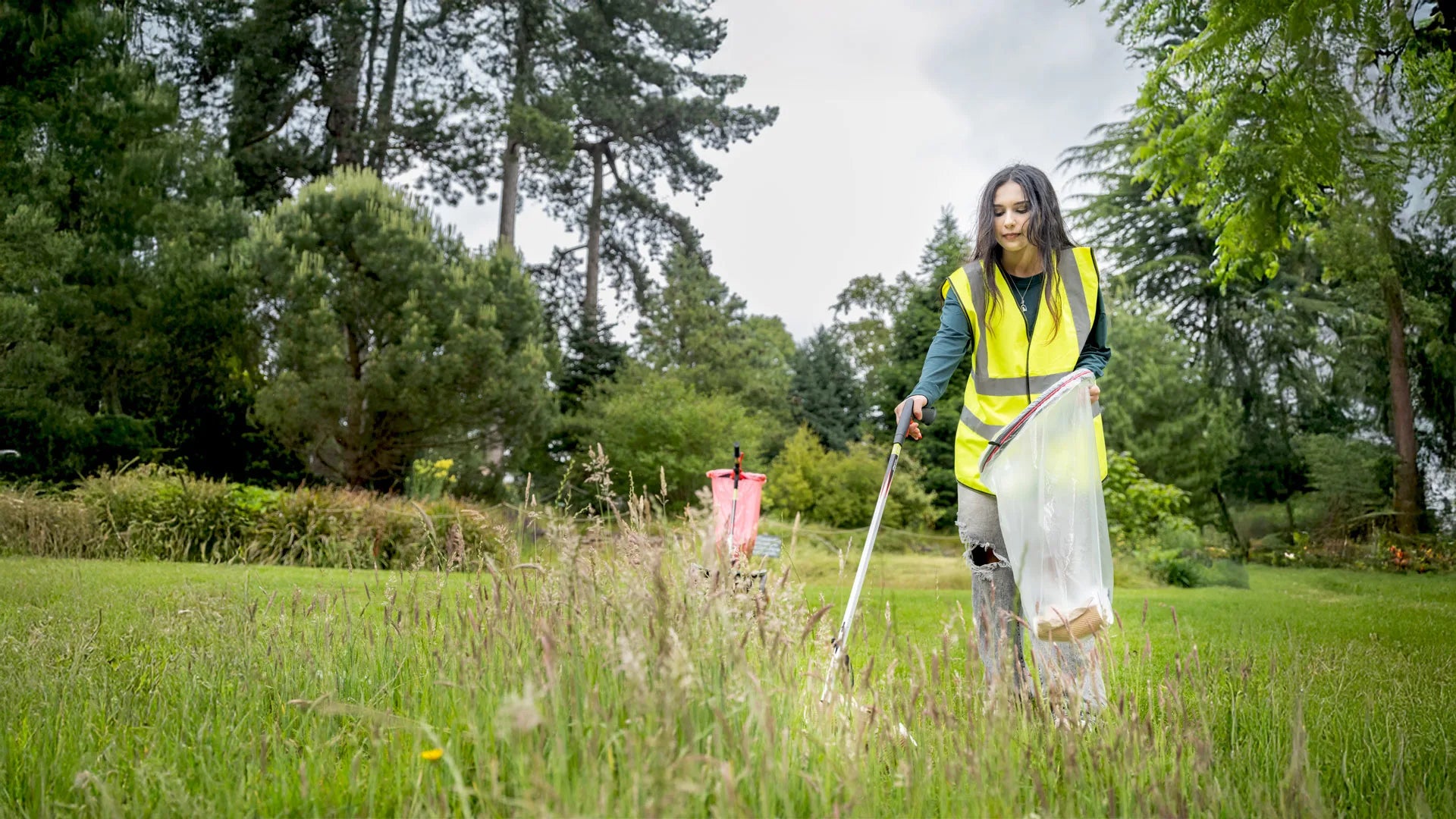 Volunteer worker picking trash with Helping Hand Litter pickers.
