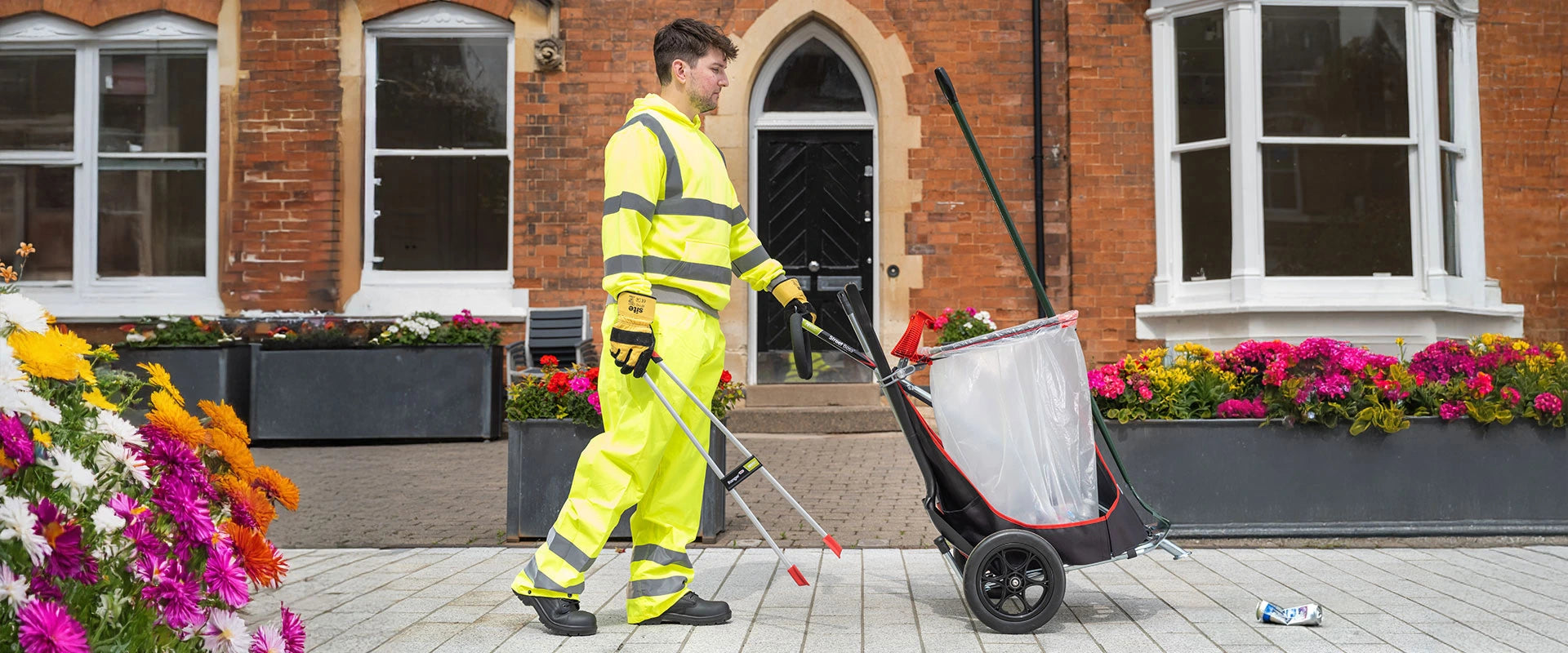 Man with cleaning trolley litter picking in residential area.
