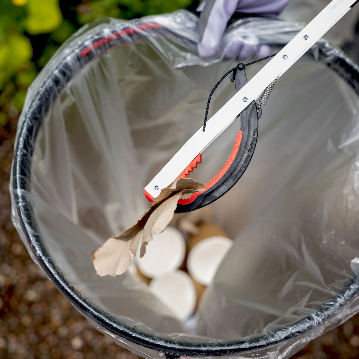 Person grabbing paper trash with Litterpicker pro folding.