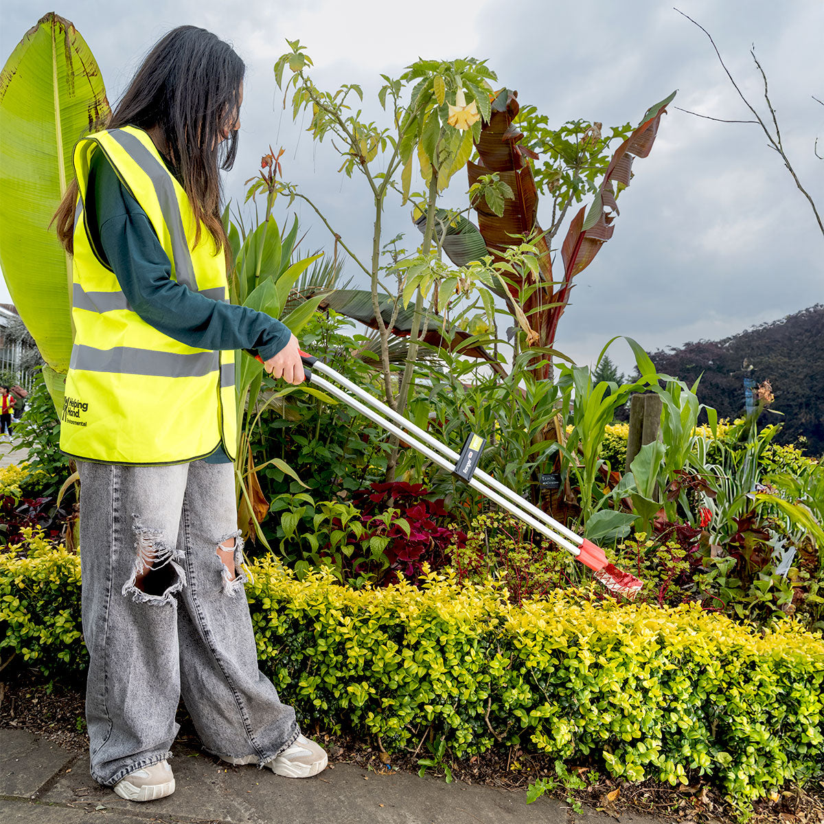 Volunteer worker picking litter from bush with the Ranger Max Curved heavy duty
