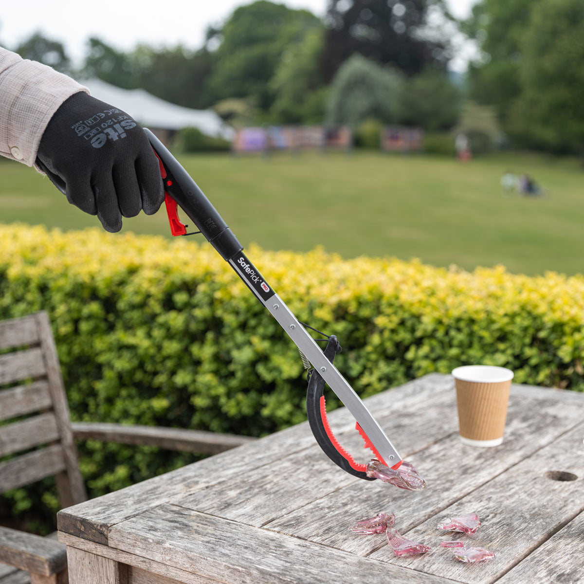 Person picking broken glass with SafepPick Pro folding litter picker.